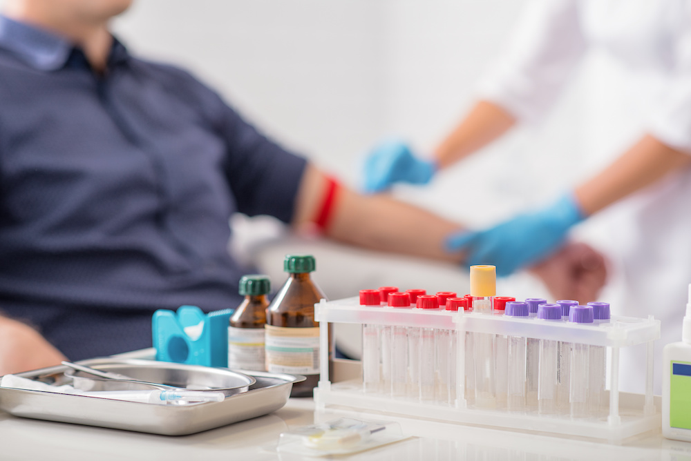 Doctor preparing patient for blood sampling for lab testing. Focus on blood test tools on table