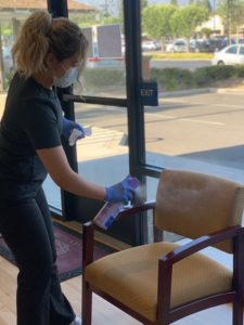 picture of haven elite staff member spraying lysol disinfectant on chair in the waiting room 
